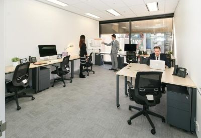 Bright open-plan office with multiple workstations and a whiteboard for collaboration.