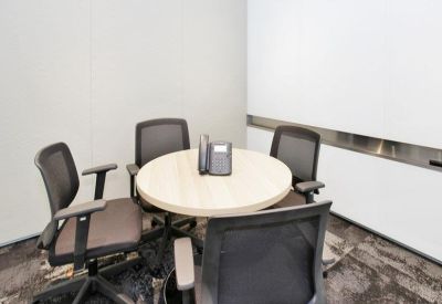 Small private meeting room with a round table and grey ergonomic chairs.
