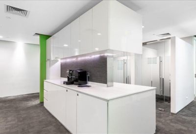 Sleek white office kitchen with a coffee machine and modern lighting.