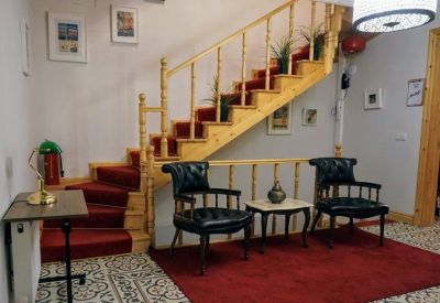 Communal lounge area featuring a wooden staircase, red rug, and leather armchairs.