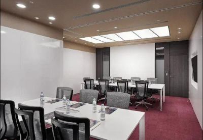 Spacious boardroom with a large conference table, red carpet, and whiteboards.