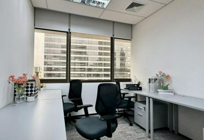Internal four-person office suite with white desks, black ergonomic chairs, and large windows.
