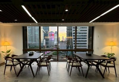 Open-plan coworking area with dark wood tables, contemporary chairs, and floor-to-ceiling windows.