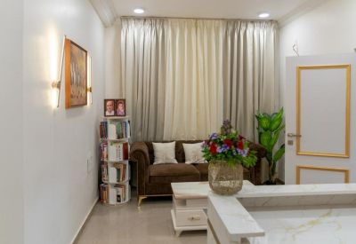 Waiting lounge with a brown velvet sofa, white marble coffee table, and bookshelves.