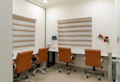 Four-person workstation area with leather rolling chairs and striped window shades.