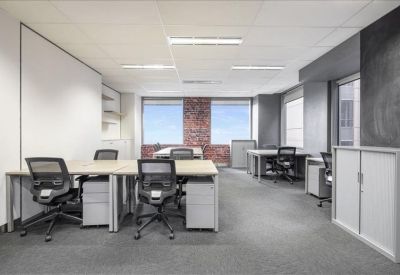 Bright open-plan office with grey workstations and a red brick feature wall.
