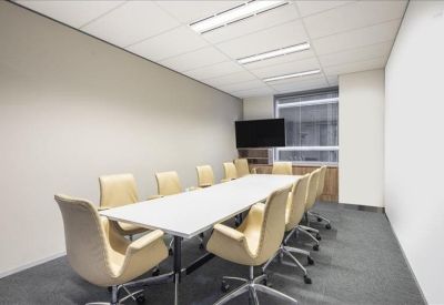 Formal boardroom featuring a long white table and cream leather chairs.
