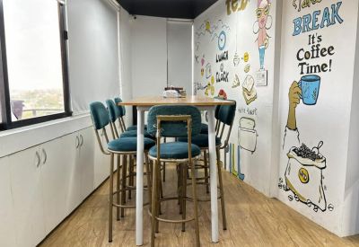 Communal break area with high-top seating and colorful coffee-themed wall illustrations.