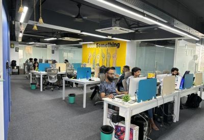 Modern open-plan office space with white desks, teal accents, and yellow motivational wall art.