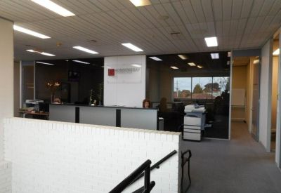Spacious reception area with a white front desk and glass-partitioned offices.