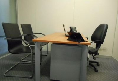Private office suite featuring a wooden desk and black guest chairs.