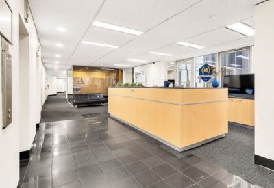 Professional reception area featuring a large wood-panelled desk and polished stone flooring.
