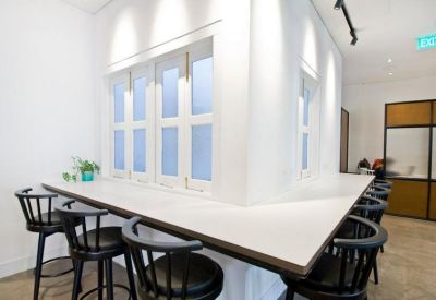Minimalist white coworking space with a wrap-around counter and black wooden bar stools.