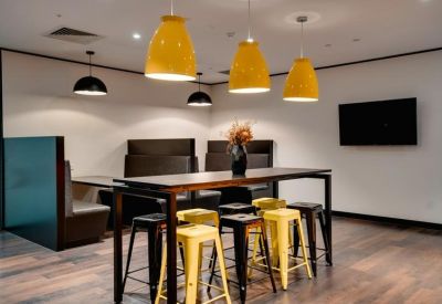Communal break area with high tables and vibrant yellow pendant lights.