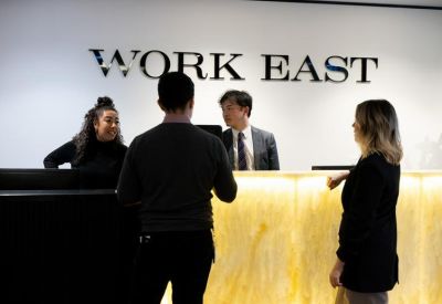 Reception area with backlit onyx desk and staff under Work East signage.