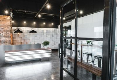 Modern industrial reception area with a backlit front desk and brick feature wall.