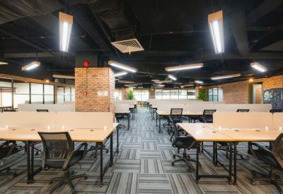 Wide open-plan office with numerous workstations, carpeted floors, and industrial ceilings.