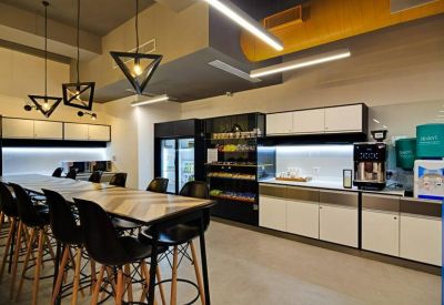 Sleek office kitchen and pantry area with a chevron-patterned breakfast bar and black high chairs.