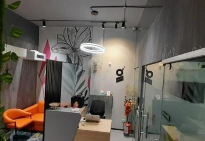 Reception area with a light wood front desk, orange accent seating, and a decorative leaf mural.