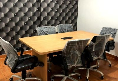 Conference room with a large wooden table, grey mesh chairs, and a tufted accent wall.