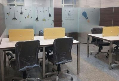 Open-plan workspace with white desks, grey mesh chairs, and yellow privacy dividers.