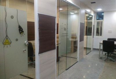 Corridor view through glass doors showing interior office cabins and tiled flooring.