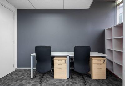 Compact private office with two workstations and a grey feature wall.