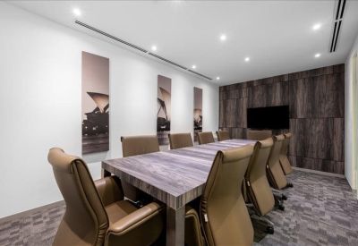 Executive boardroom with a long wooden table and brown leather chairs.
