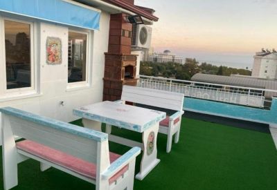 Rooftop terrace with white bench seating and artificial grass offering views of the coast.