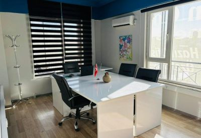 Conference room with a large white table, black chairs, and striped window blinds.
