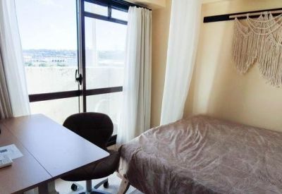 Sunny bedroom nook with a large sliding glass door and a bohemian-style macrame wall decor.