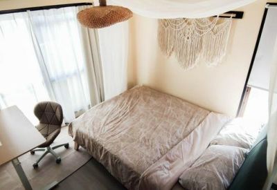 Balcony view at sunset overlooking the city streets and distant sea with patio furniture.