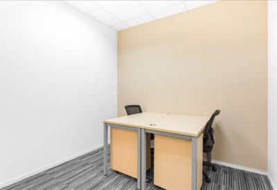 Compact two-person office suite with light wood desks and a neutral accent wall.