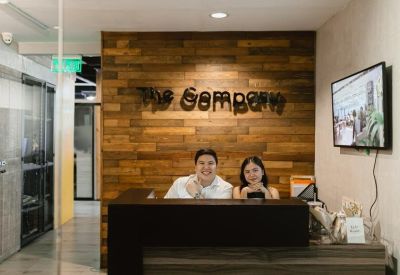 Bright reception desk with a wood-paneled feature wall and 'The Company' branding.