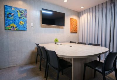 Modern meeting room with a large oval table, black chairs, and colorful wall art.