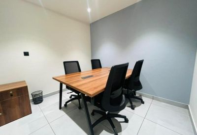 Professional four-seat meeting room with a wooden table and minimalist grey accent wall.