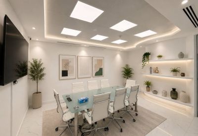 A professional meeting room with a frosted glass table, white chairs, and modern lighting.