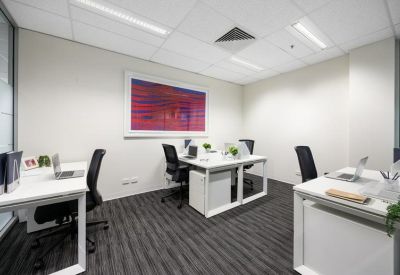Bright four-person private office with modern white desks and colorful wall art.