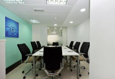 Modern conference room featuring a large white table, black ergonomic chairs, and a teal accent wall.