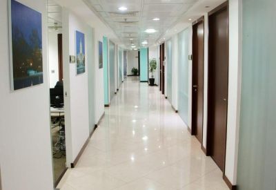 Bright office corridor with white tiled flooring and glass-partitioned suites.