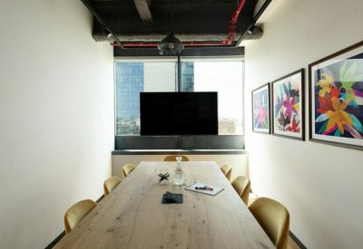 Minimalist meeting room with a long light wood table and floral wall art.