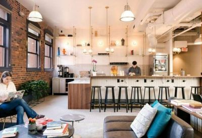Modern office kitchen and bar area featuring brick walls and blue velvet seating.