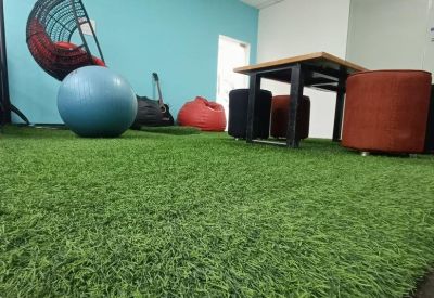 Casual breakout area with artificial grass flooring, a bean bag, and a hanging pod chair.