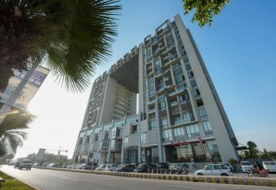 Low angle exterior of the modern AJ Towers building with a unique central archway and high-rise facade.