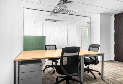 Bright private office with a light wood desk, glass partitions, and three black mesh chairs.