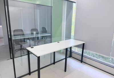 Bright corner workspace with a white desk and glass partitions.