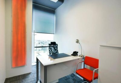 Bright private office with white desk, ergonomic chair and red accent chair.