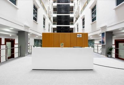 Sleek white reception desk positioned in a bright atrium with multiple floors visible above.