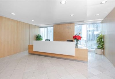 Clean, minimalist reception area with a white front desk, light wood panels, and vibrant red flowers.
