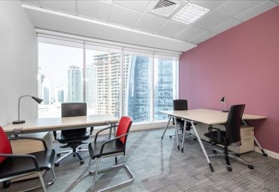 Bright corner office suite with light wood desks, red accent chairs, and floor-to-ceiling windows.